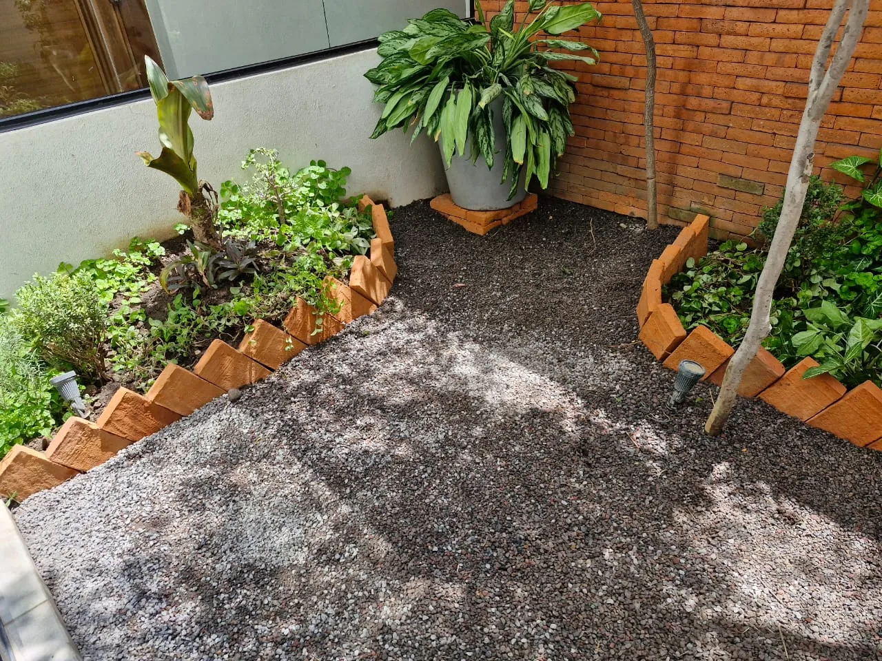 Jardineras con borde de barro y cama de grava en patio interior